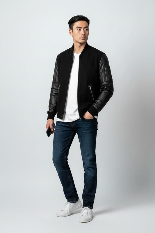 Scarlett Stitch Men's black bomber jacket with genuine leather sleeves, ribbed collar, cuffs, and hem. Features zippered pockets.
