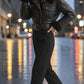 Scarlett Stitch black faux leather cropped moto jacket with faux shearling collar and cuffs, worn by a model on a city street.