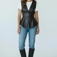 Scarlett Stitch black faux leather peplum vest with notched lapel and single-button closure, worn over a white tee and jeans.