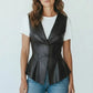 Scarlett Stitch black faux leather peplum vest with notched lapel and single-button closure, worn over a white tee and jeans.