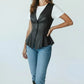 Scarlett Stitch black faux leather peplum vest with notched lapel and single-button closure, worn over a white tee and jeans.