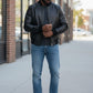 Scarlett Stitch men's black leather bomber jacket with ribbed collar, cuffs, and hem. Model wears it with a grey t-shirt and blue jeans.