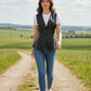 Scarlett Stitch black leather peplum vest with notched lapel and single-button closure, worn over a white tee and jeans.