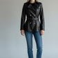 Scarlett Stitch black leather double-breasted jacket with silver buttons, waist belt, and epaulettes on a model.