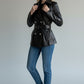 Scarlett Stitch black leather double-breasted jacket with silver buttons, waist belt, and epaulettes on a model.