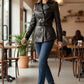 Scarlett Stitch black leather double-breasted jacket with silver buttons and waist belt worn by a woman in a cafe.