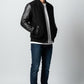 Scarlett Stitch Men's black wool-blend varsity jacket with genuine leather sleeves, snap front, and welt pockets.