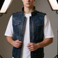 Model wearing a Scarlett Stitch distressed blue leather utility vest with snap-button pockets and a stand-up collar.