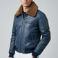 Scarlett Stitch men's blue leather bomber jacket with a brown faux-fur collar, ribbed cuffs, and utility sleeve pocket.