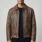 Model wearing a Scarlett Stitch brown distressed leather bomber jacket with a structured collar and front zipper.
