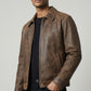 Scarlett Stitch men's brown distressed leather bomber jacket with a structured collar and front zipper.