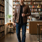 Scarlett Stitch brown faux leather bomber jacket with stand collar, zippered front, and ribbed cuffs. Model wears jeans and t-shirt.