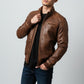 Scarlett Stitch brown faux leather bomber jacket with stand collar, zippered front, and ribbed cuffs. Detailed stitching and zippered pockets.