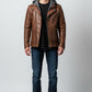 Scarlett Stitch men's brown distressed leather motorcycle jacket with a grey knit hood worn by a model.