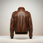 Scarlett Stitch Men's brown leather bomber jacket with ribbed collar, cuffs, and hem. Features epaulets and zip closure.