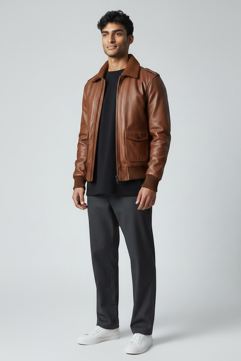 Scarlett Stitch Men's genuine leather bomber jacket in warm brown with ribbed collar, cuffs, and hem. Features zip closure and flap pockets.