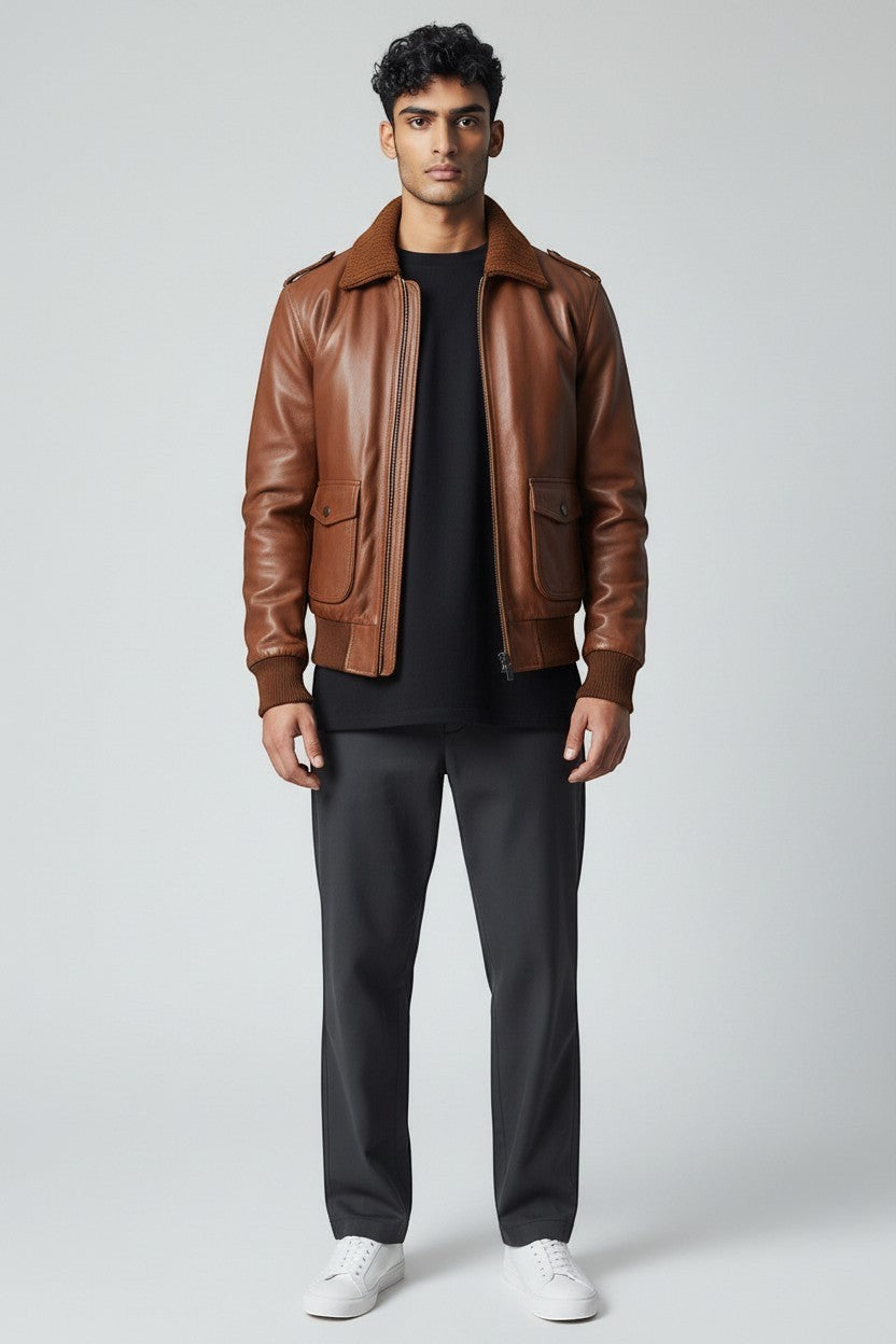 Scarlett Stitch Men's genuine leather bomber jacket in warm brown with ribbed collar, cuffs, and hem. Features zip front and flap pockets.