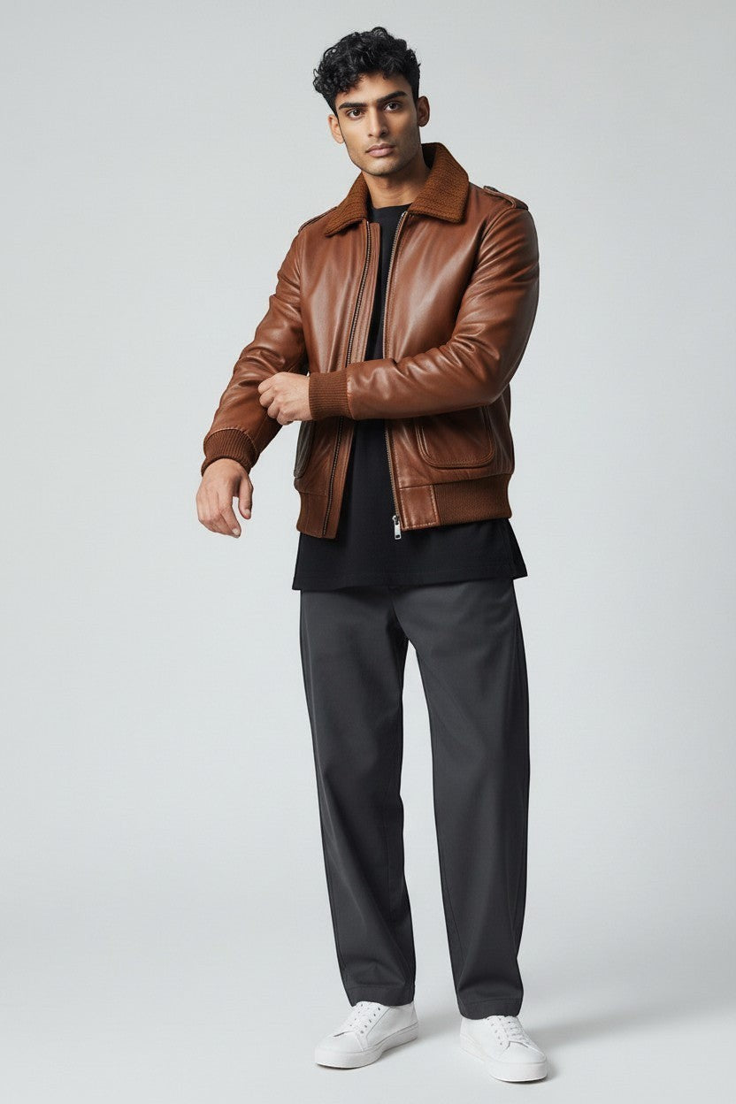 Scarlett Stitch Men's brown genuine leather bomber jacket with ribbed collar, cuffs, and hem. Features zipper, flap pockets, and epaulets.