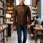 Man wearing a Scarlett Stitch brown leather jacket with a stand-up collar and zippered pockets in a library cafe.