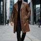Scarlett Stitch men's distressed brown leather double-breasted trench coat worn by a model in a city setting.