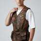 Scarlett Stitch brown distressed leather utility vest with multiple snap pockets and adjustable waist belt on a model.