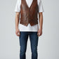 Scarlett Stitch distressed brown leather vest with V-neck, button front, and flap pockets, worn over a white t-shirt.