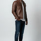 Man wearing a brown Scarlett Stitch faux leather utility jacket with chest pockets and stand-up collar over a white tee