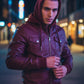 Scarlett Stitch burgundy faux leather hooded bomber jacket with zip front and chest pockets on a man at night.
