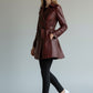 Model wearing a Scarlett Stitch burgundy faux leather double-breasted belted trench coat with black jeans and sneakers