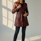 Scarlett Stitch burgundy faux leather double-breasted trench coat with a belted waist worn by a model.