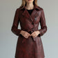 Model wearing a Scarlett Stitch burgundy faux leather double-breasted belted trench coat with notched lapels.