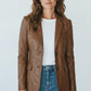 Scarlett Stitch cognac brown leather blazer with notched lapels and two-button closure worn by a woman with jeans.
