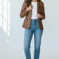 Model wearing a Scarlett Stitch cognac brown leather blazer with notched lapels over a white tee and blue jeans.