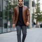 Man wearing a Scarlett Stitch cognac brown leather blazer with notch lapels over a black tee and grey trousers.