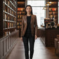 Scarlett Stitch distressed brown leather blazer worn by a woman in a library setting with black jeans and sneakers.