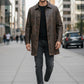 Scarlett Stitch men's distressed brown vintage leather car coat worn by a man walking on a city sidewalk.