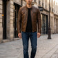 Scarlett Stitch men's distressed brown leather cafe racer jacket with quilted shoulders worn on a city street.