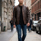 Scarlett Stitch men's distressed brown leather jacket with quilted shoulders and mandarin collar worn on city street.