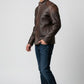 Scarlett Stitch men's distressed brown leather jacket with quilted shoulders and mandarin collar worn with jeans.