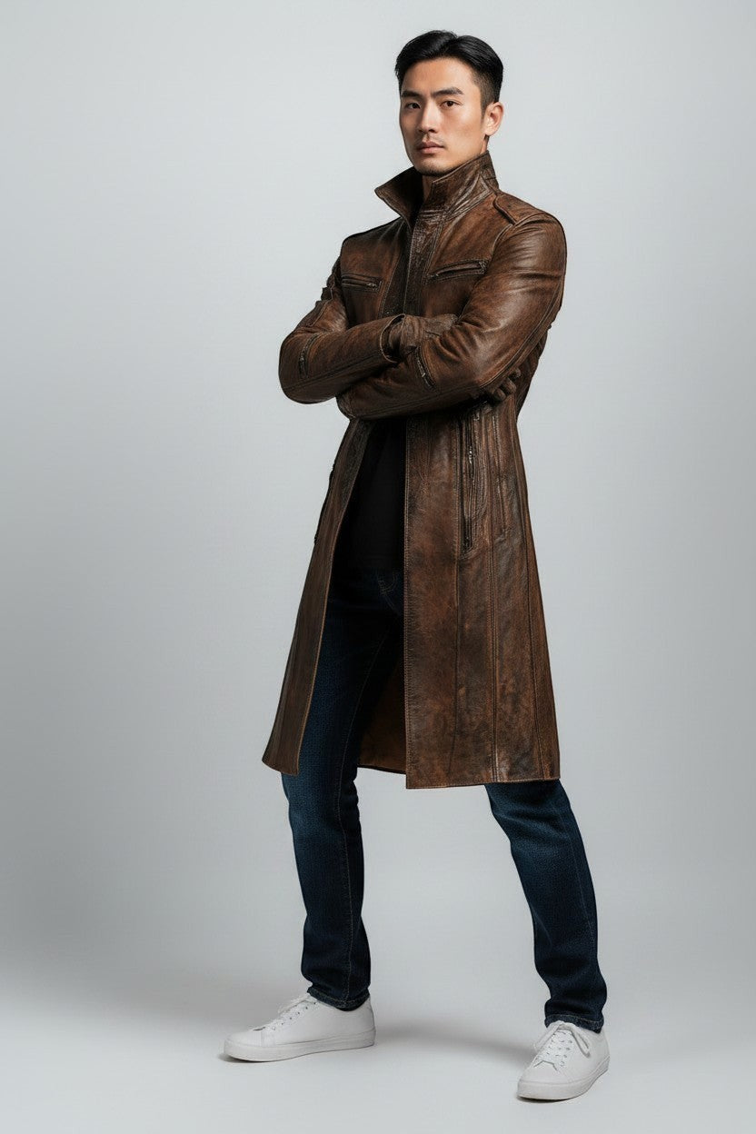 Scarlett Stitch men's distressed brown leather trench coat with a high-neck collar and zippered pockets on a model.