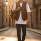 Man wearing a Scarlett Stitch brown distressed leather biker vest over a white t-shirt on a sunlit city street.