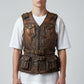 Scarlett Stitch brown distressed leather utility vest with multiple snap pockets and adjustable waist belt on a model.