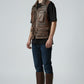 Model wearing a Scarlett Stitch brown distressed leather utility vest with multiple pockets and a zip-front closure.
