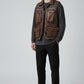Model wearing a brown distressed leather utility vest by Scarlett Stitch with multiple pockets and zip closure.
