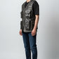 Man wearing a Scarlett Stitch distressed leather utility vest with multiple pockets over a black t-shirt and jeans.