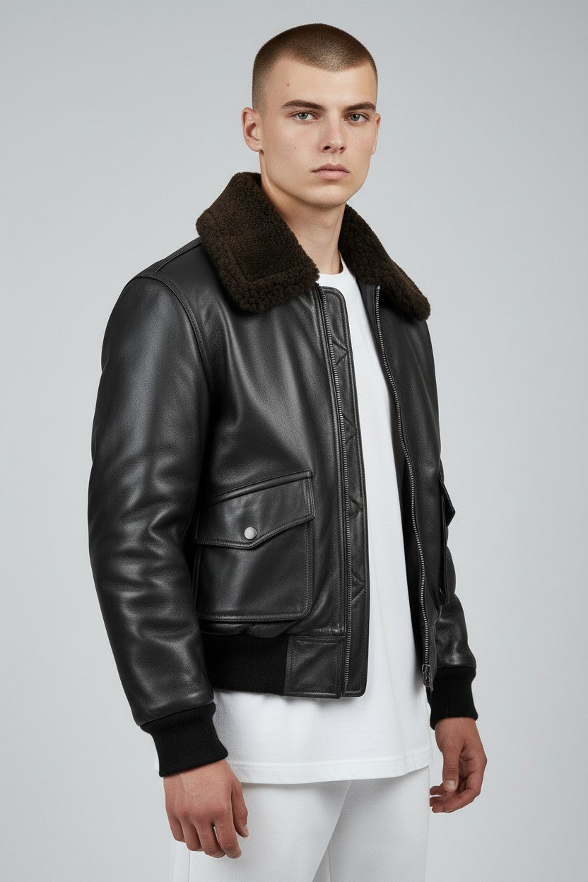 Scarlett Stitch Men's black faux leather bomber jacket with dark brown shearling collar, ribbed cuffs and hem, zip front, and flap pockets.