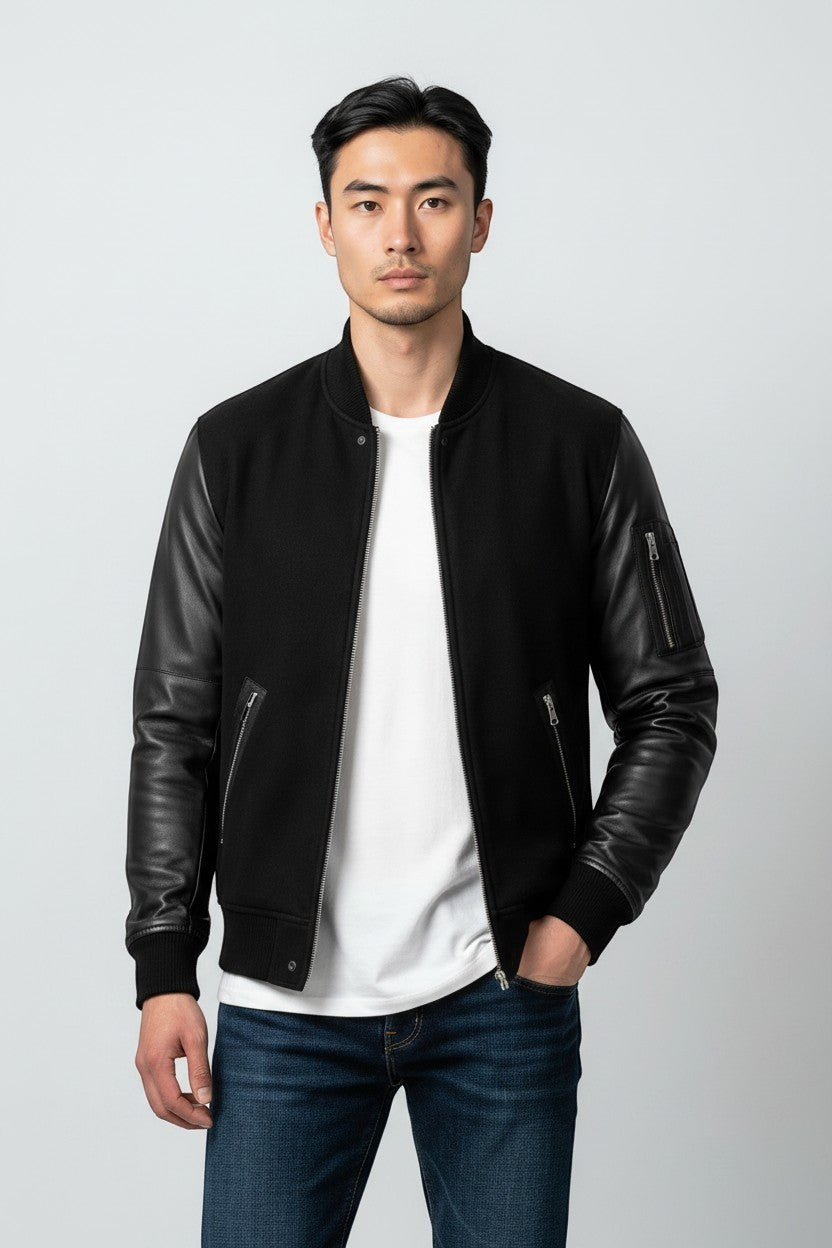 Scarlett Stitch Men's black bomber jacket with genuine leather sleeves, ribbed collar, cuffs, hem, and zippered pockets.