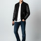 Scarlett Stitch Men's black bomber jacket with genuine leather sleeves, ribbed collar, cuffs, and hem. Features zippered pockets.