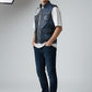 Model wearing a Scarlett Stitch distressed blue leather utility vest with front pockets over a white t-shirt.