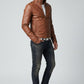 Model wearing a brown Scarlett Stitch faux leather jacket with a stand collar, white t-shirt, and dark denim jeans.